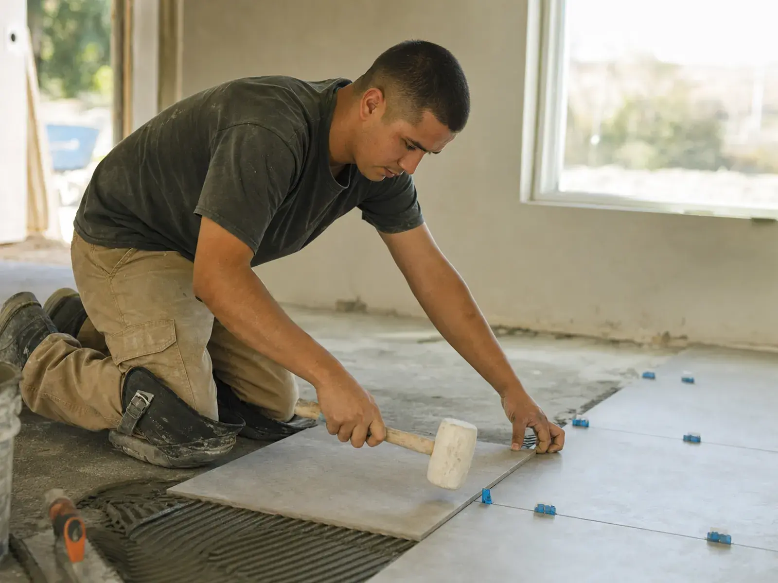 Un instalador de azulejos colocando piso de porcelanato grande con separadores